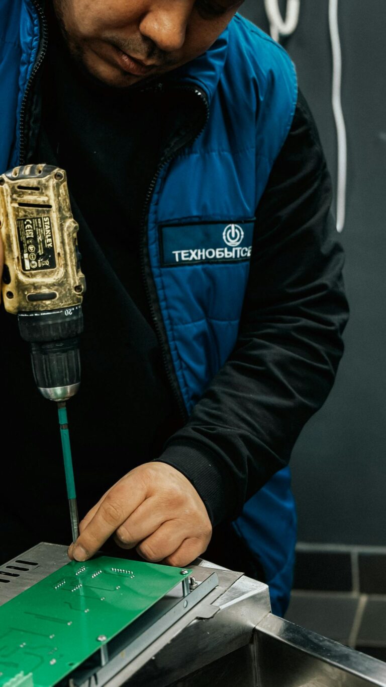 Man working with a drill on a circuit board, demonstrating precision and expertise in technology assembly.